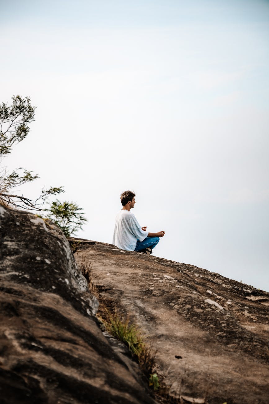 man meditating on the top of a hill